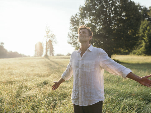Mann steht in der Morgensonne in einem Feld