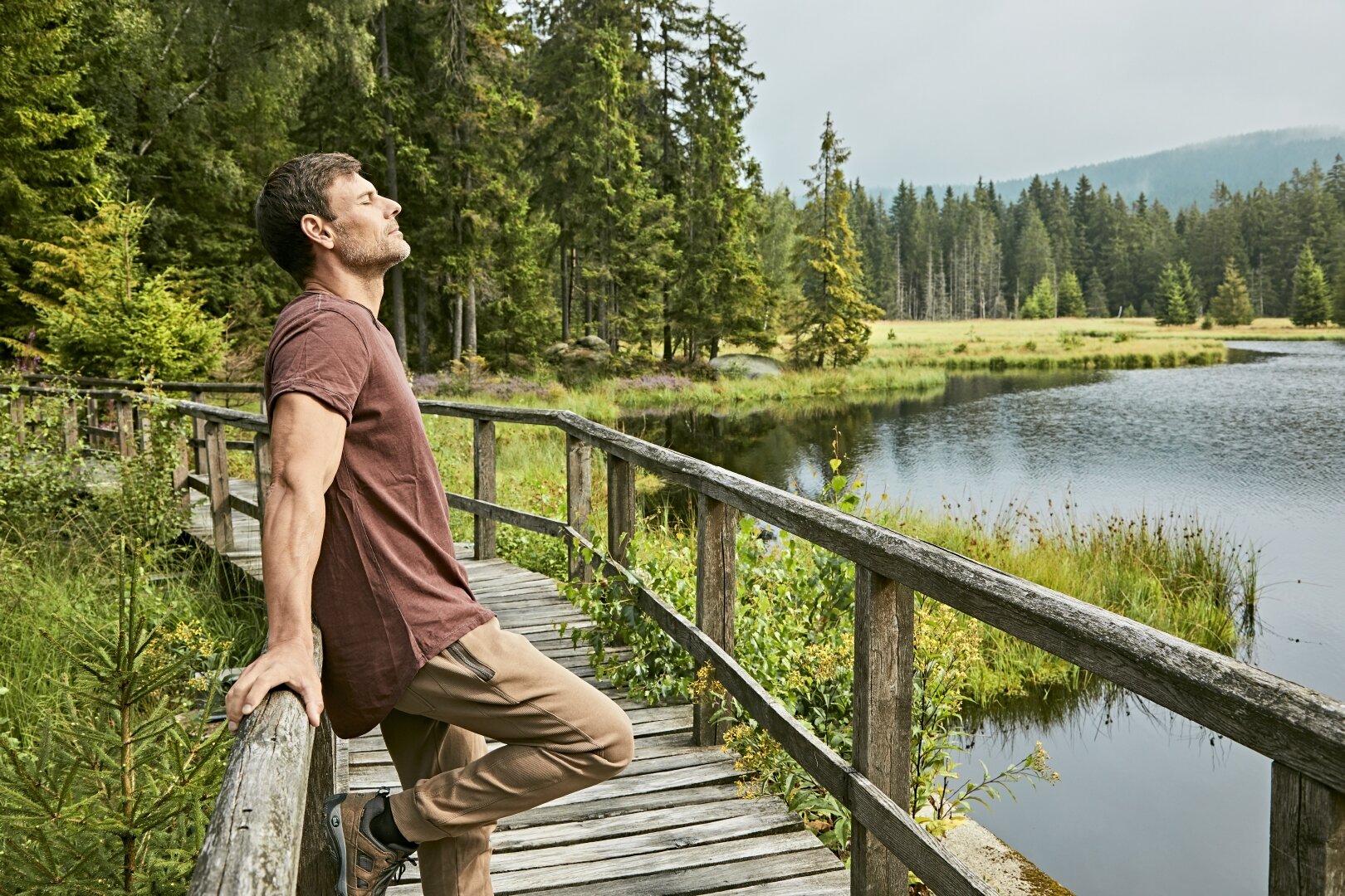 Gesundes Bayern - Mann am Steg nahe See atmet tief ein, Thema Heilklima