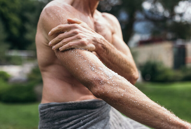 Mann reibt seine Arme mit dem Heilmittel Salz bei der Solekur ein