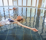 Sie sehen eine junge Frau in einem Heilbad entspannt treiben.