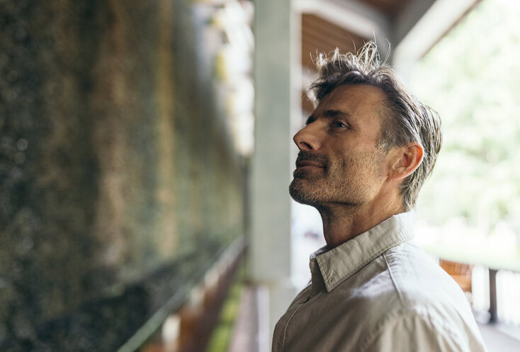 Mann in Gedanken vor einer grünen Wand die für Heilklima sorgt