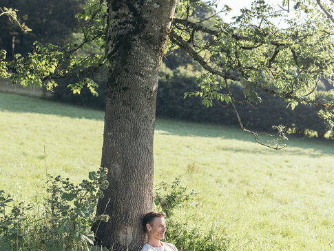 Mann liest ein Buch unter einem Baum