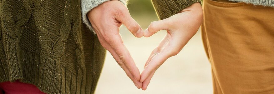Hier sehen Sie wie zwei Personen mit ihren Händen ein Herz formen. 