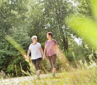 Gesundes Bayern - 2 Damen spazieren an einem sonnigen Tag durch schöne Natur