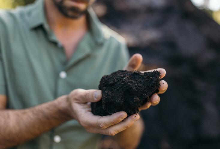 Mann hält Erde in seinen Händen, die für die Moorkur verwendet wird