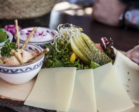 Sie sehen ein Käsebrett für die Brotzeit auf einem Tisch stehen.