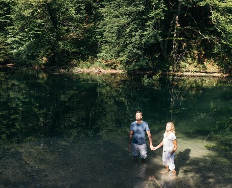 Paar steht in der Sonne und hält Händchen im Wasser