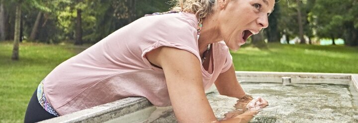 Hier sehen Sie eine Frau, die ihre Unterarme in ein Becken mit klarem Wasser taucht.