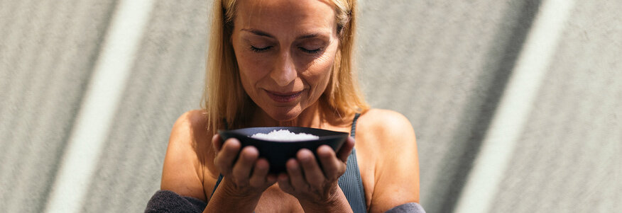 Frau hält heilsames Salz in den Händen und meditiert