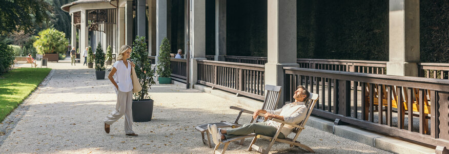 Kurpark, Frau geht, Mann auf Liegestuhl